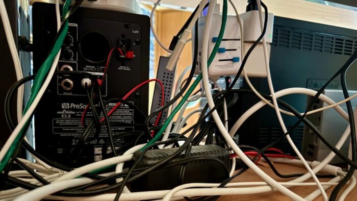 A jumbled mess of wires and cables seen from behind a monitor and computer box.
