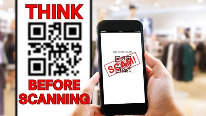 Racks in a clothing store are blurry in the background. Person holding an iPhone is in the foreground. Screen reads QR code in black and a big red SCAM! banner across the actual QR code. Behind the phone is a large QR code on a white background with big red text above and below the QR code reading think before scanning