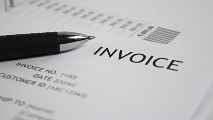 Printed copy of an invoice on white paper with a black pen laid across the left side of the page.