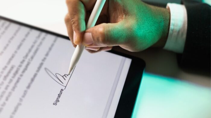 hand of a man signing his signature on an iPad using an Apple Pencil