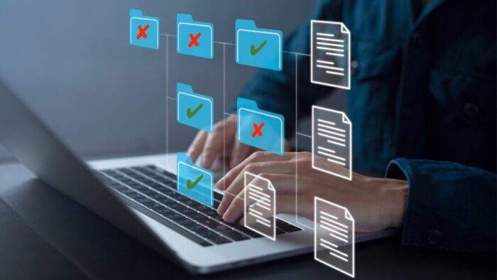 blurred background of a person typing at an open Mac laptop. digital overlay of Mac folder and file icons in a grid pattern. half of the folders have a red X over them and half have a green check on them.