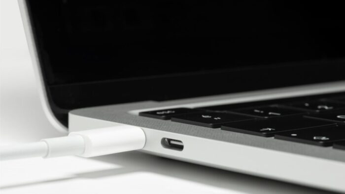 close up of the left side of an open Mac laptop. a cord is plugged into one of the two USB-C ports.