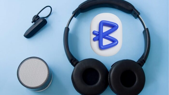 three bluetooth devices on a light blue background. an ear piece, a small speaker, and over the ear headphones. inside the headphones is a drawing of the bluetooth B symbol.