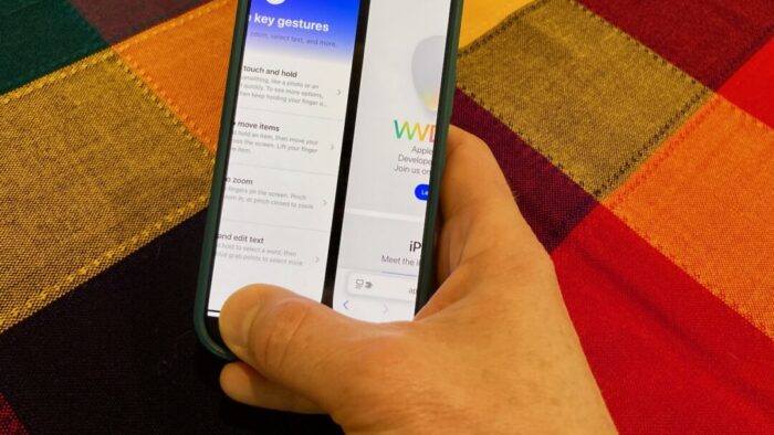 a person's right hand holding an iPhone that is switching between apps. background is a red, orange, and yellow large checkered tablecloth.