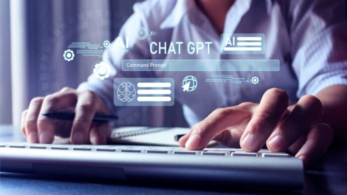 close up of a person's hands on a keyboard with their body blurred in the background. digital overlay of "chat GPT" and a space to enter info.