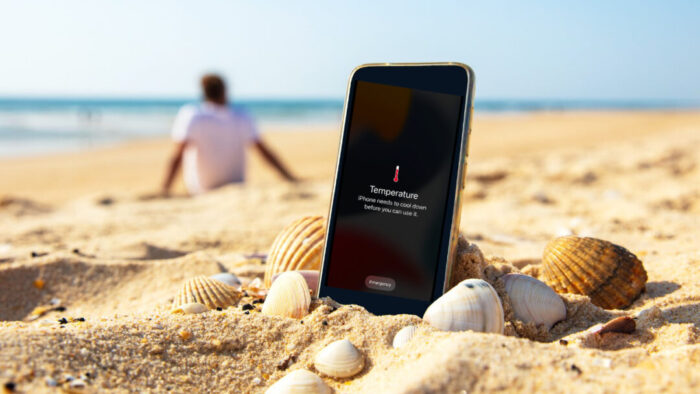beach scene. close up of an iPhone nestled in the sand with a heat warning on screen