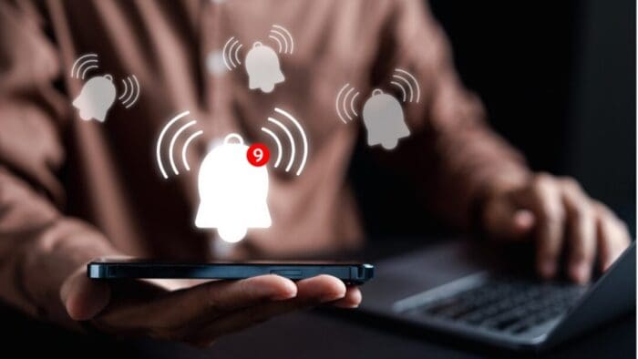 blurred pic of the torso and arms of a person using a computer. white bell icons overlay the image.