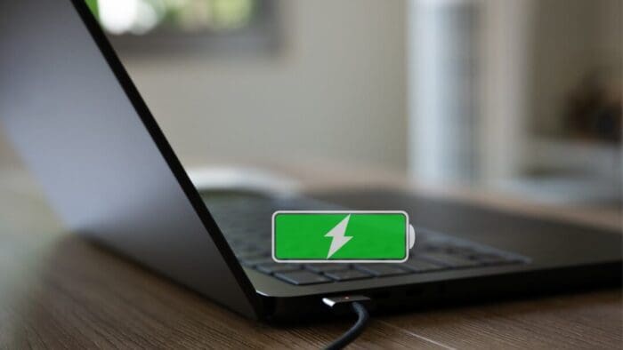 Open laptop on a desk. There's a green full and charging battery indicator drawn over the laptop