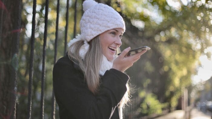 woman standing outdoors speaking into her phone