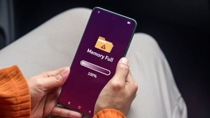 an over the shoulder downward view of a person holding an iPhone in their lap with a "memory full" message displayed on the screen